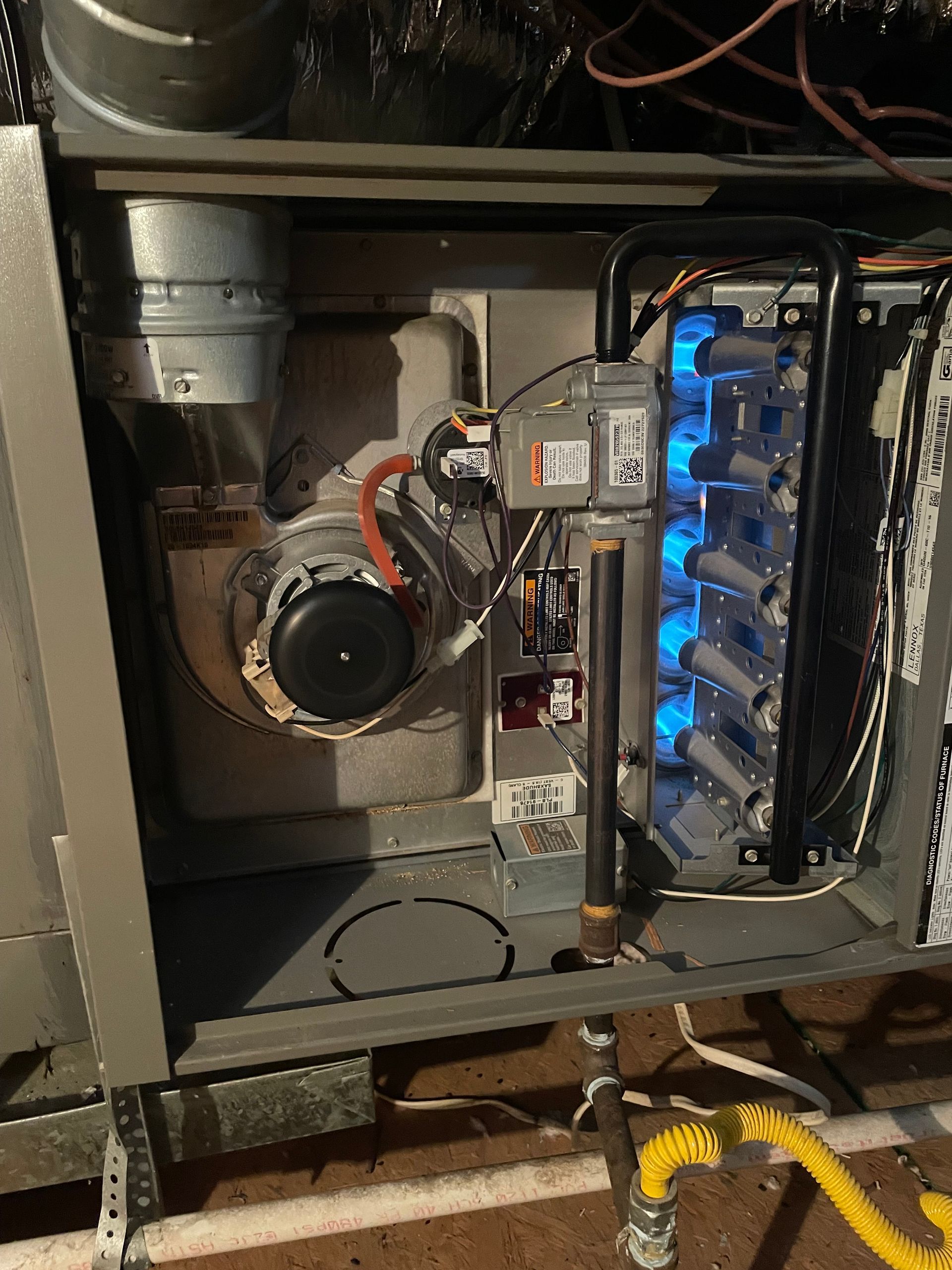 HVAC Furnace Repair - Interior of a gas furnace featuring a draft inducer motor, gas valve, and blue lit burners.