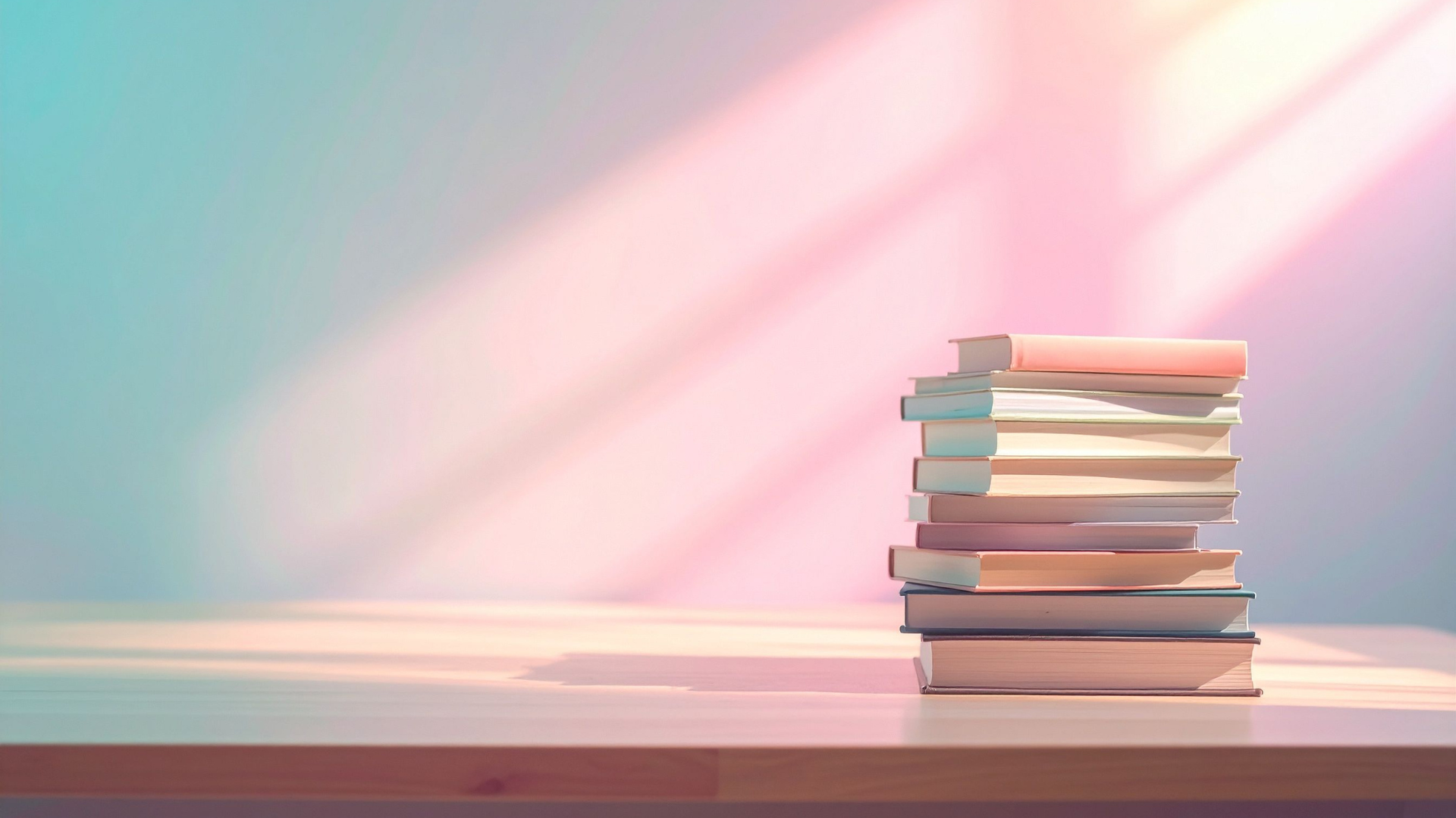 Stack of books on a pastel pink surface with soft sunlight and rainbow light streaks in the background