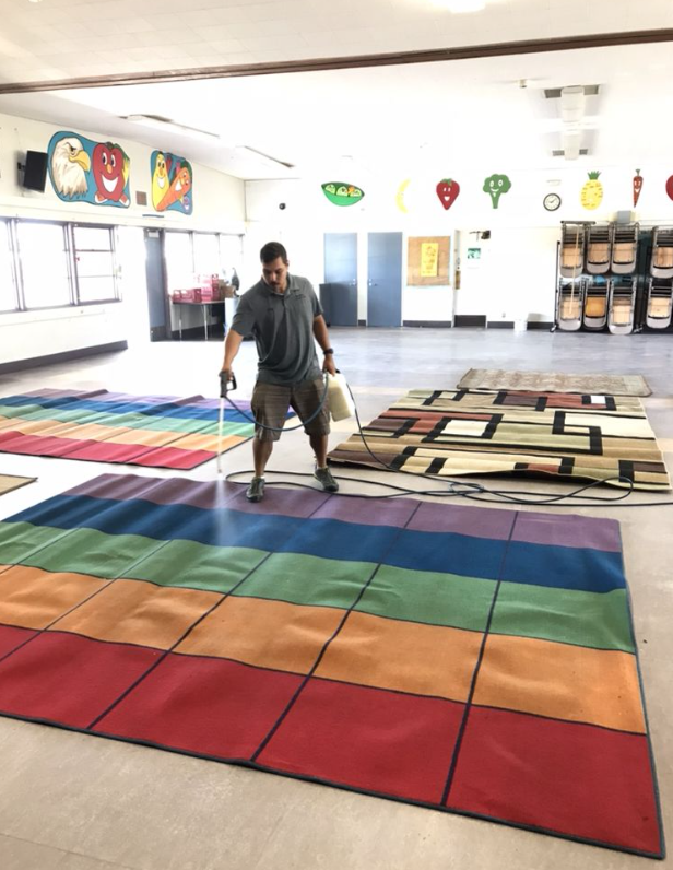 Person standing in a bright room with colorful rugs laid out on the floor