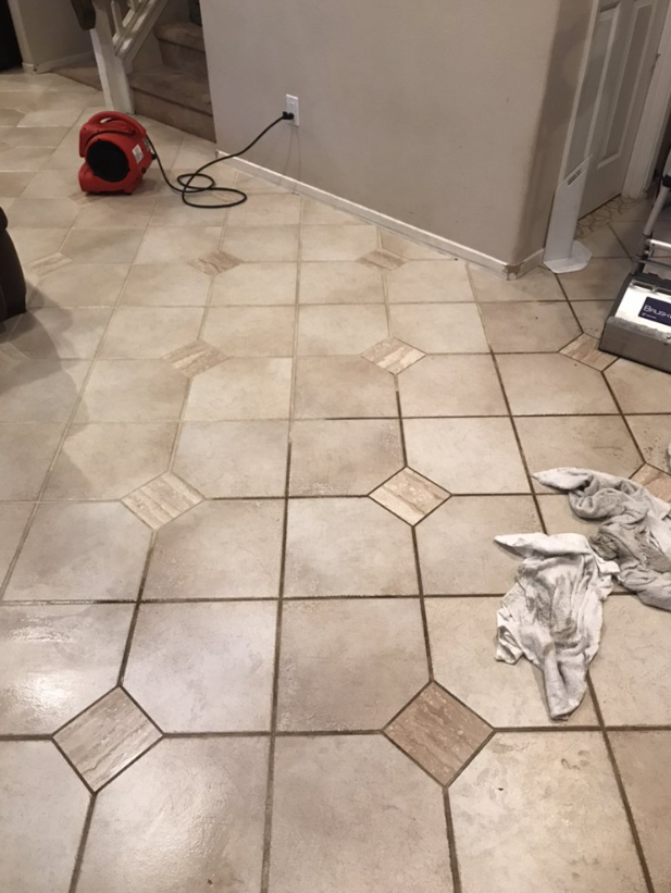 Tiled kitchen floor with a red vacuum, cord, and a pair of crumpled white socks near a doorway.