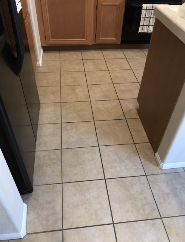Kitchen floor with beige tile and wooden cabinets, viewed from a doorway