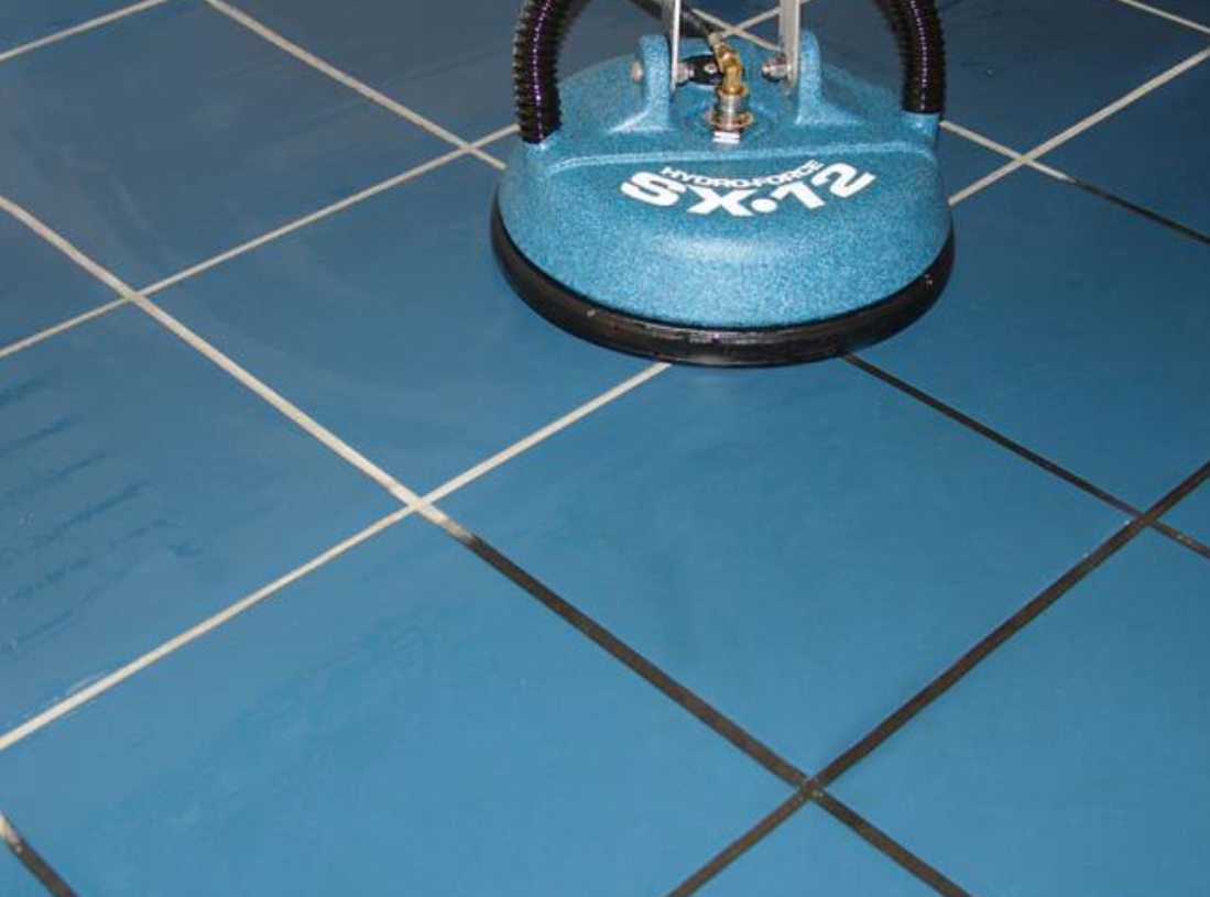 Blue tile floor being cleaned with a floor scrubber brush.
