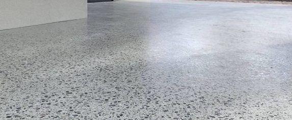 Speckled grey honed concrete floor with a bright reflection near the center.