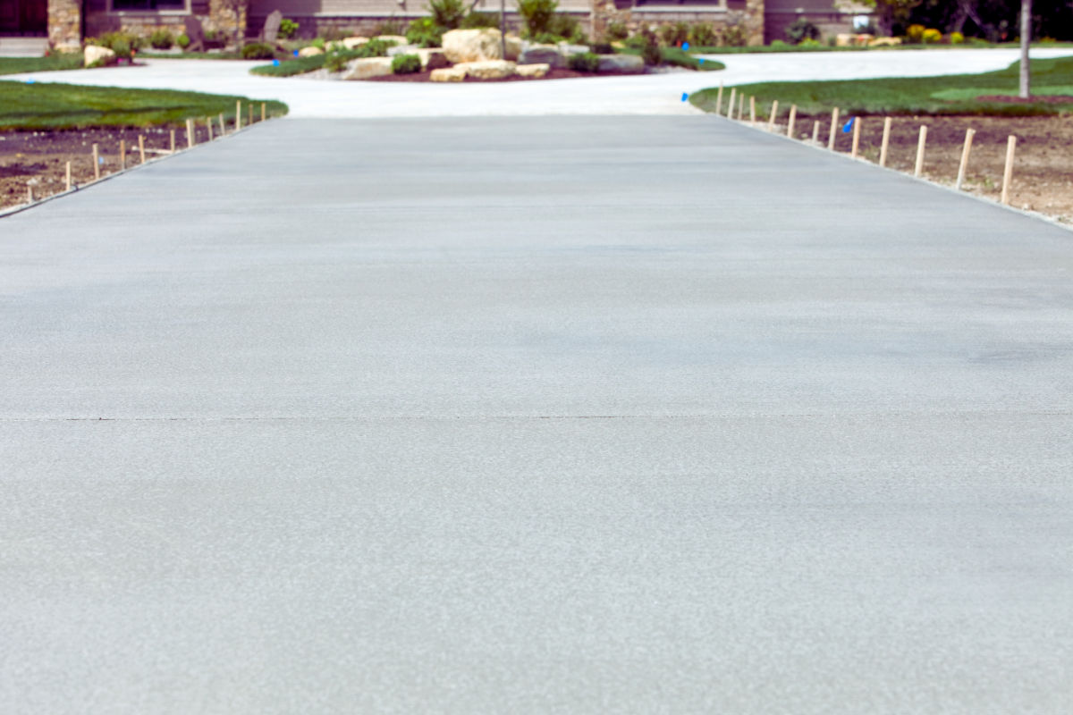 Close up of standard grey concrete driveway leading to house at the end.