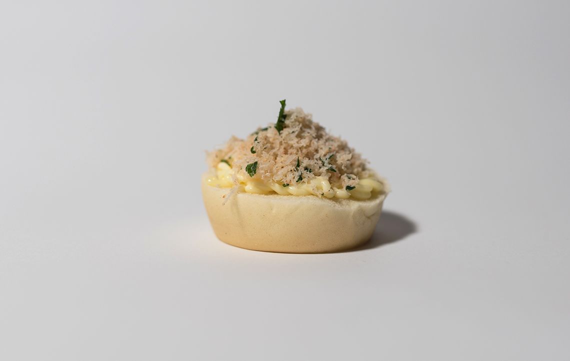 Mini ciotola di pane farcita con panna e guarnita con carne sfilacciata.