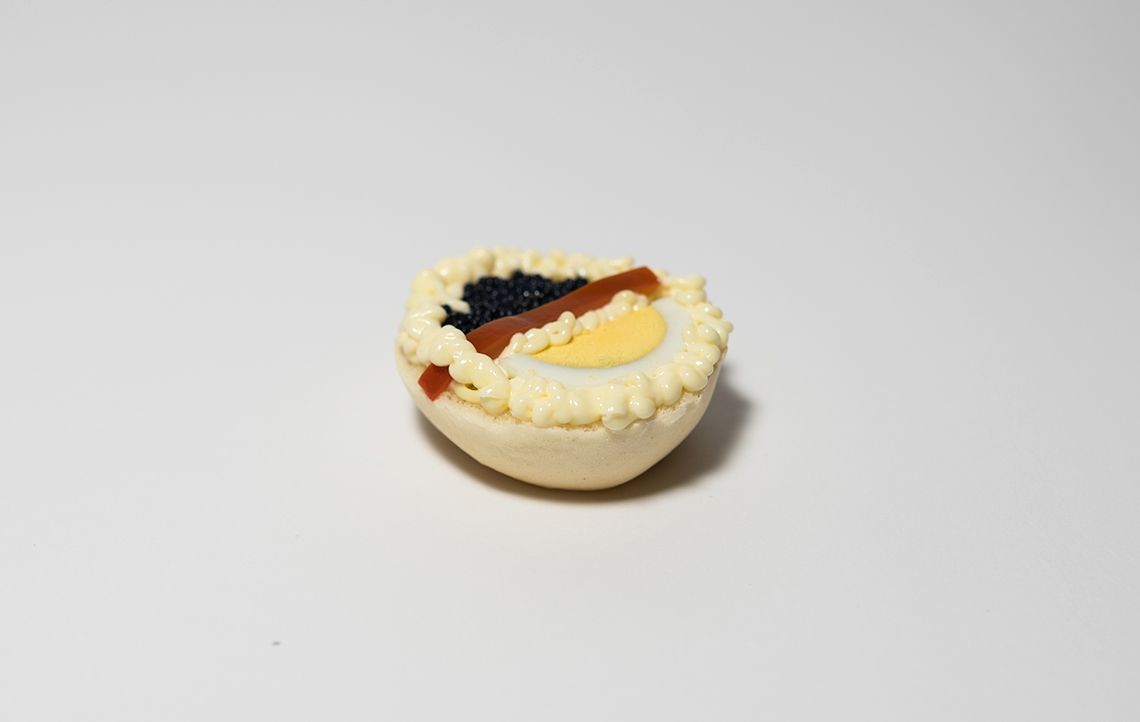 Mini crostata di pasta sfoglia con ripieno di uova, caviale nero e salsa.