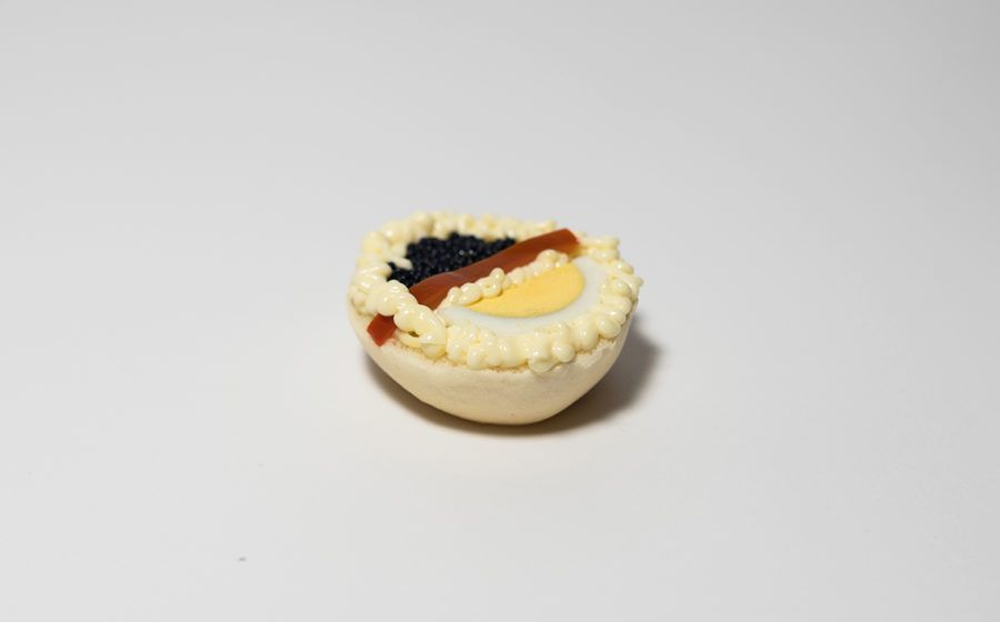 Mezzo uovo alla diavola, ripieno cremoso guarnito con caviale nero, tuorlo e glassa rossa.