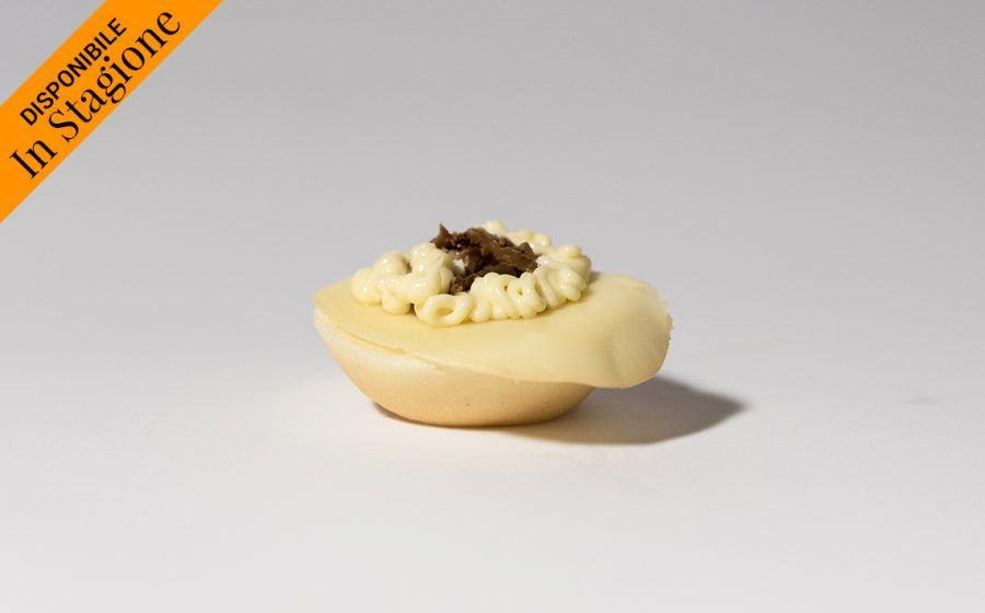 Antipasto con crema di copertura e guarnizione scura, su una base di colore chiaro, su una superficie bianca.