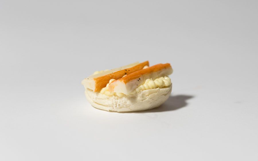 Mini panino al granchio su superficie bianca.