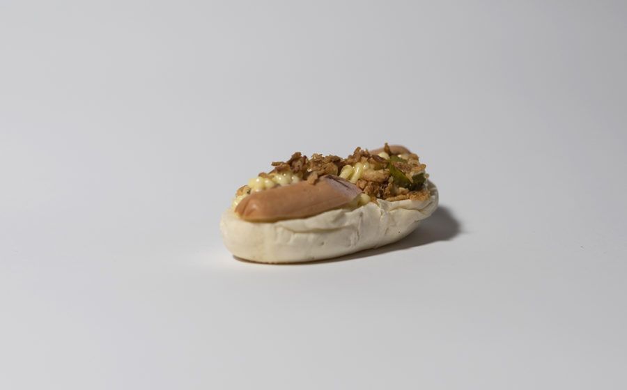 Hot dog in un panino, condito con relish e cipolle tritate. Sfondo bianco.