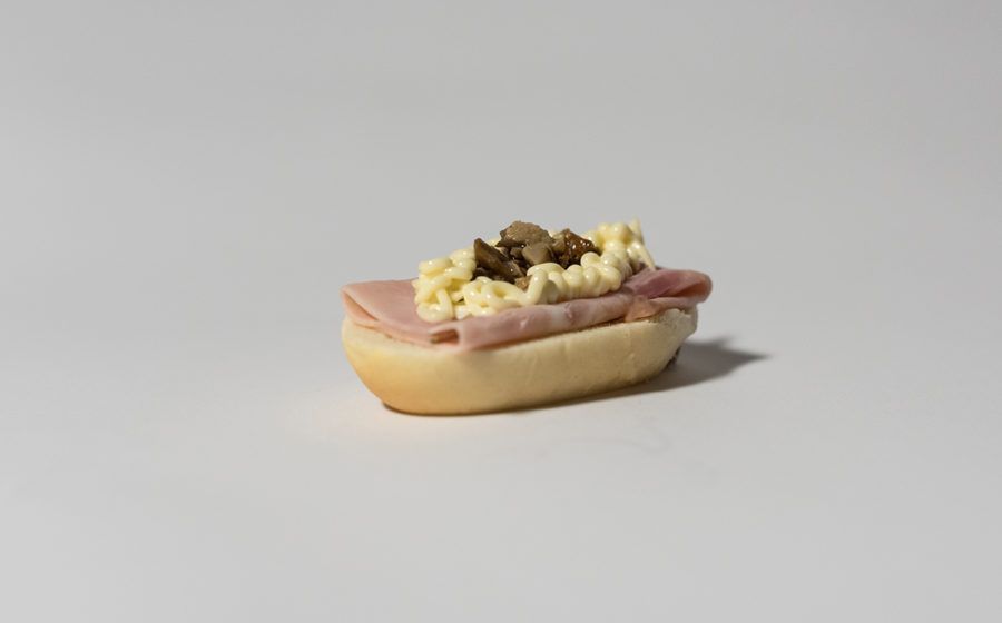 Piccolo panino su sfondo bianco: prosciutto, insalata di uova e funghi.