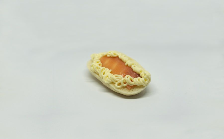 Un piccolo dolce ovale con ripieno color salmone e bordo color crema, su sfondo bianco.