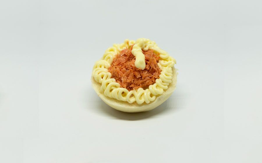 Mezzo uovo alla diavola, bordo giallo crema, ripieno arancione, sfondo bianco.