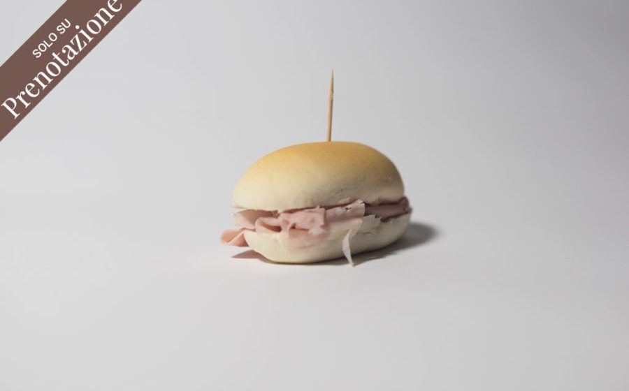 Piccolo panino ripieno di carne, tenuto insieme da uno stuzzicadenti su una superficie bianca.