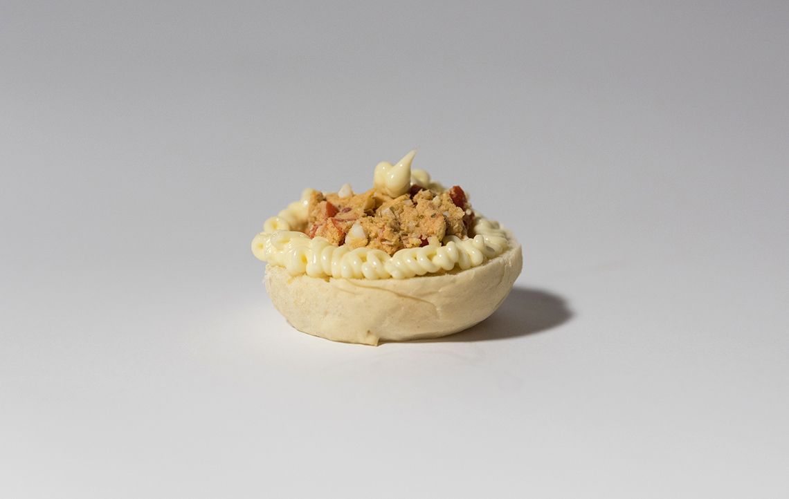 Un piccolo guscio di pasta sfoglia ripieno di una crema gialla e guarnito con pezzetti di colore marrone chiaro.