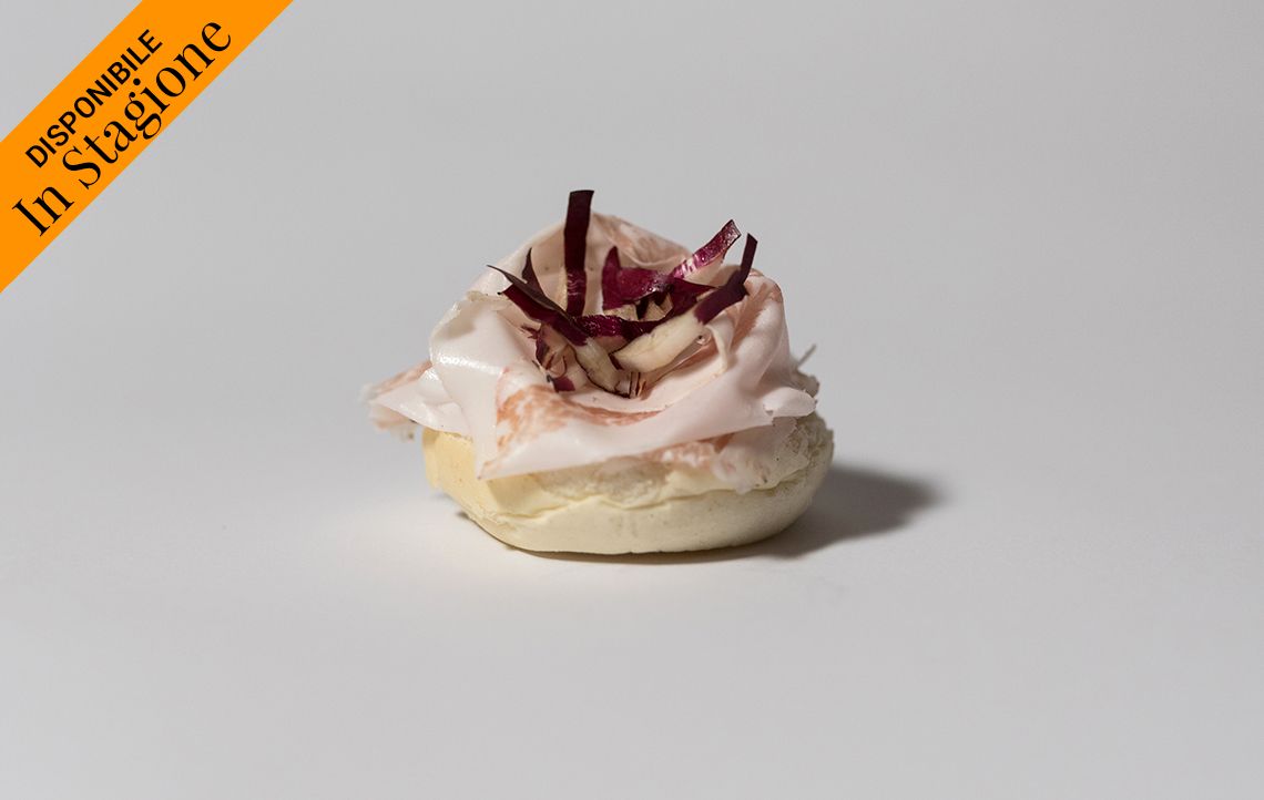 Piccola pasta sfoglia bianca guarnita con carne rosa, contorno di verdure rosse e l'etichetta 