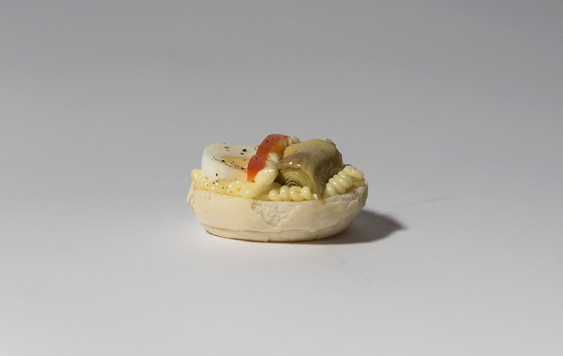 Antipasto singolo su una superficie bianca, con uova, salsa e verdure all'interno di una base simile al pane.
