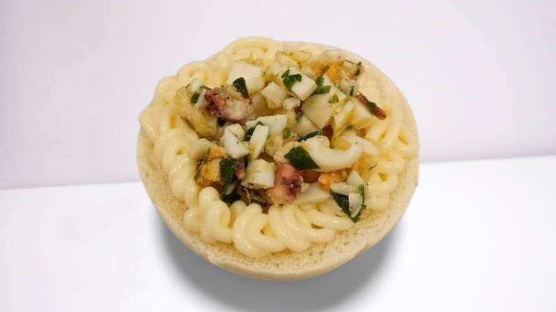 Antipasto in una ciotola di pane ripiena di salsa cremosa e verdure a dadini.