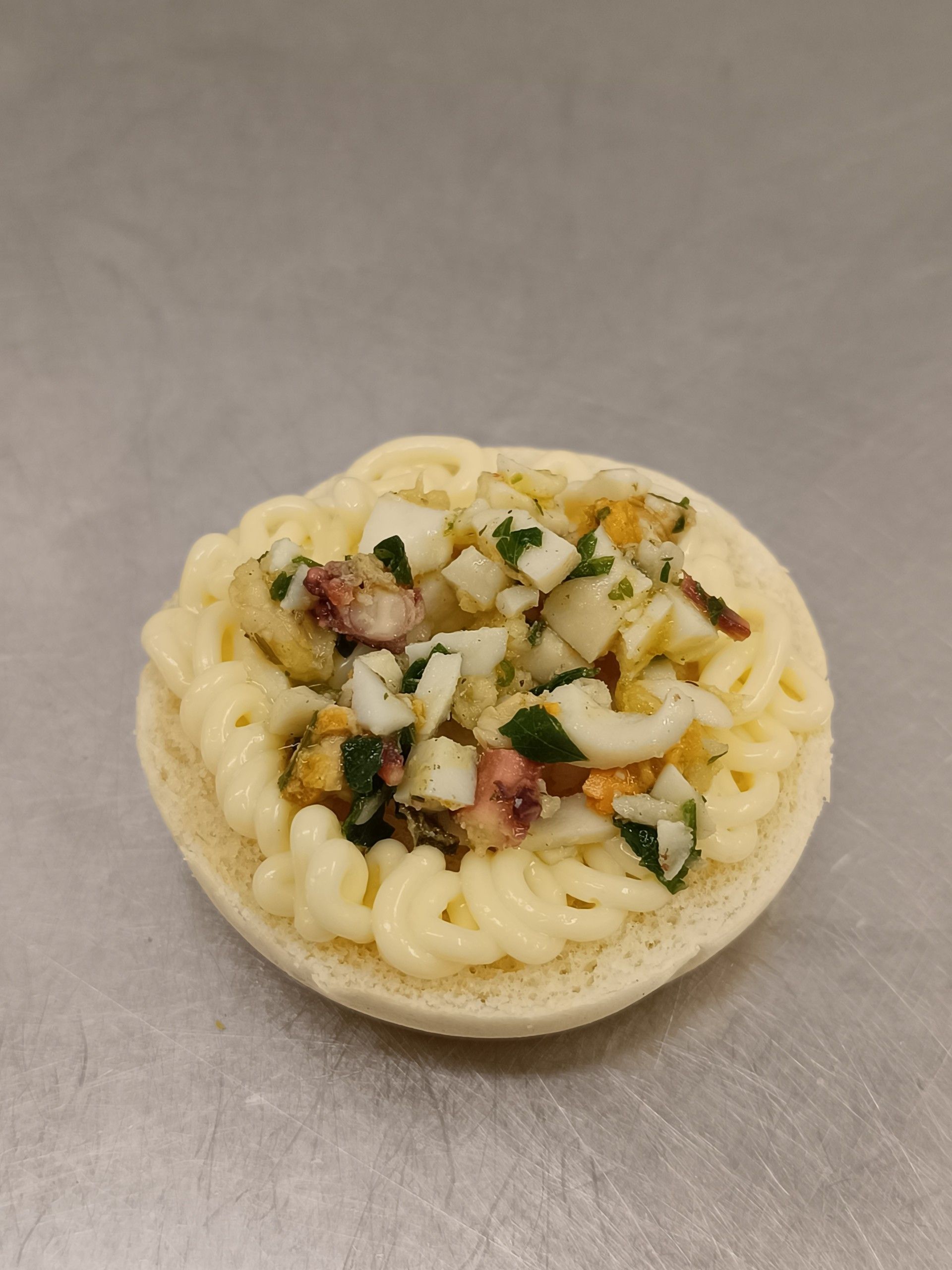Insalata di uova su un panino, con base di maionese e uovo tritato, prezzemolo e calamari.