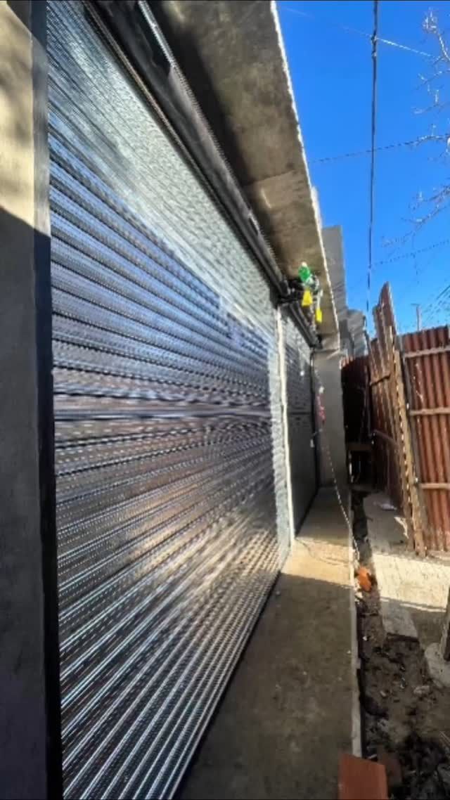 Persiana metálica enrollable que cubre una puerta en el exterior de un edificio,.