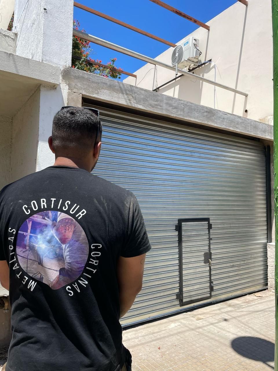 Un hombre con camisa negra se encuentra frente a una puerta metálica de seguridad cerrada