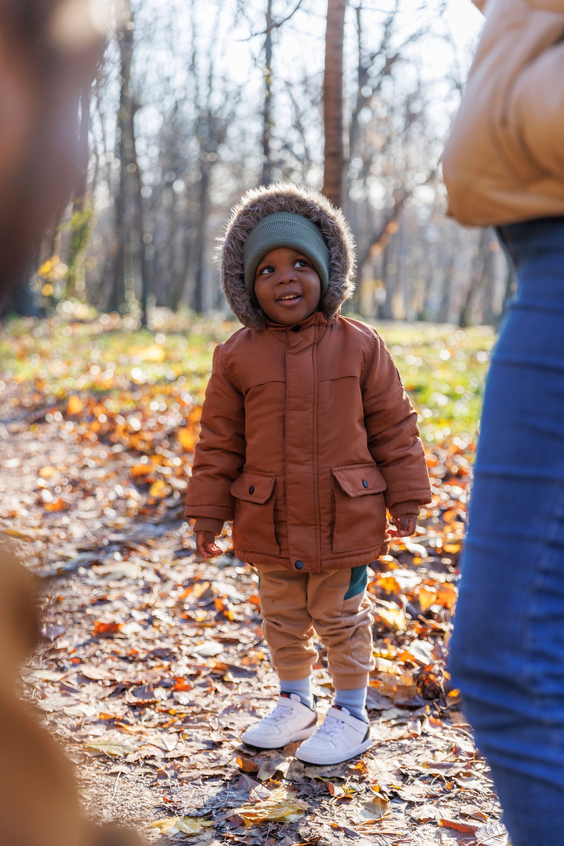A man is carrying a child on his shoulders in a park.