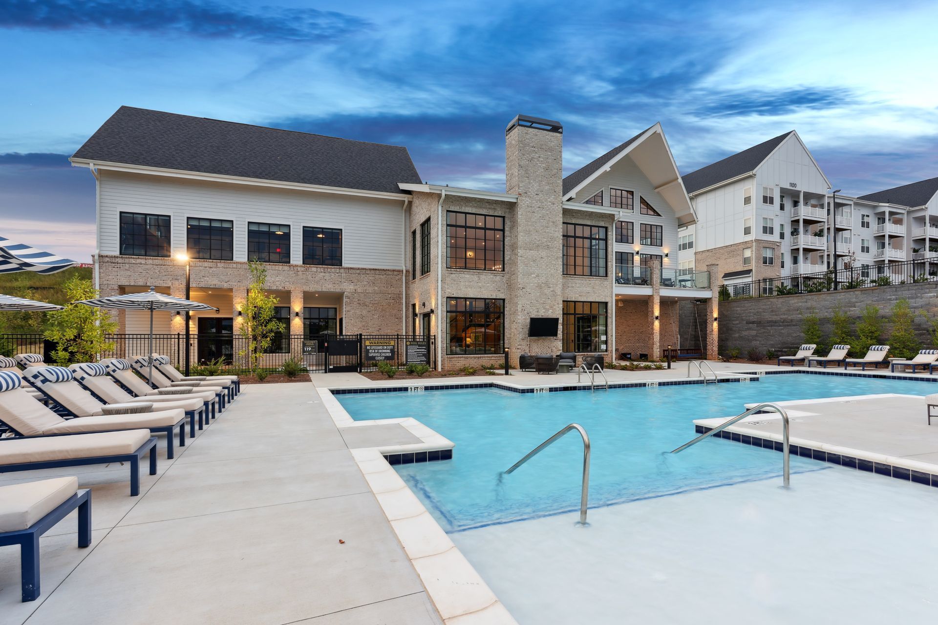 Swimming pool at luxury apartment complex, light brick and white buildings, blue sky at Upland at Emerson in Emerson, GA.
