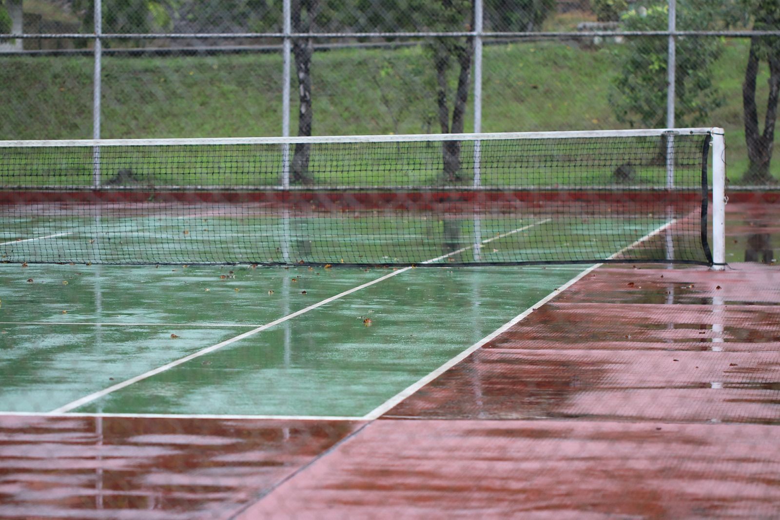 Wet outdoor tennis court with a net in the rain