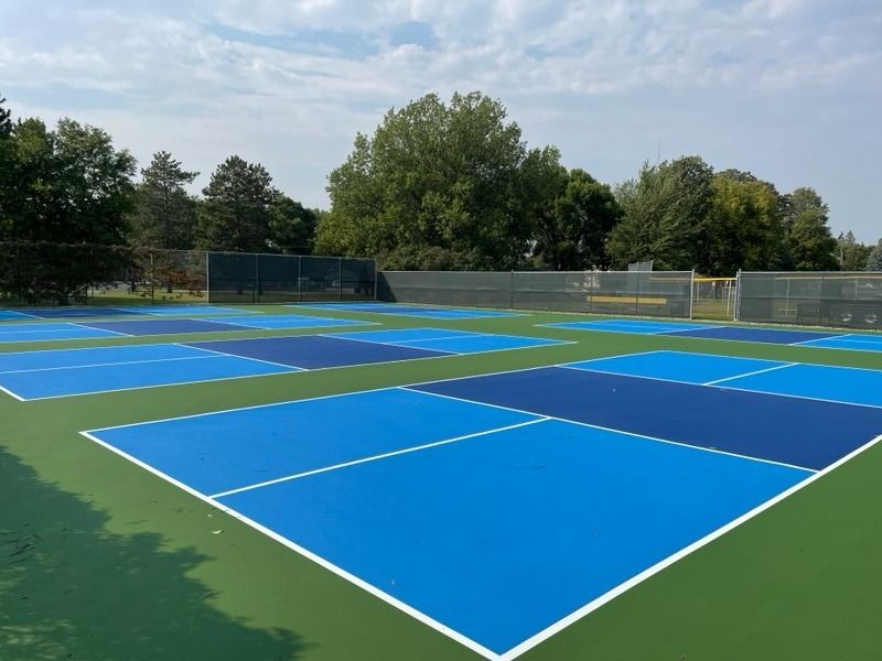 A blue and green tennis court with trees in the background