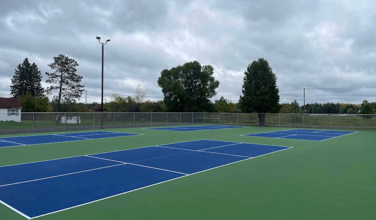 A tennis court with a fence and trees in the background