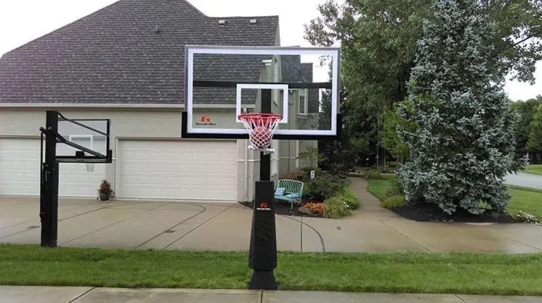 Portable basketball hoop on a driveway in front of a house and garage