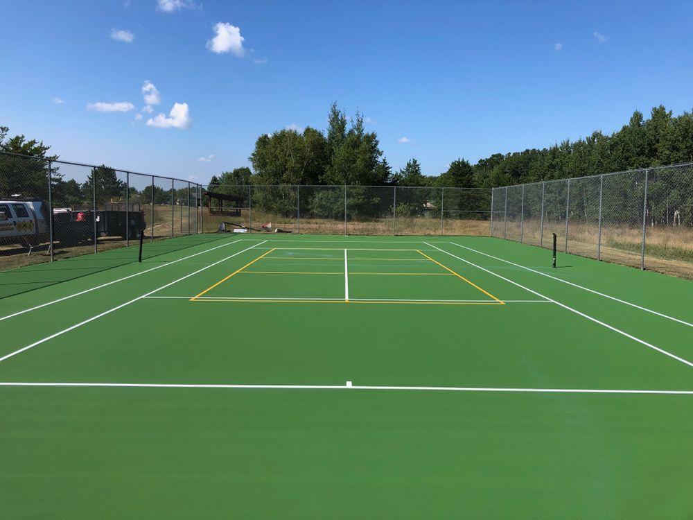 A tennis court with a fence around it on a sunny day.