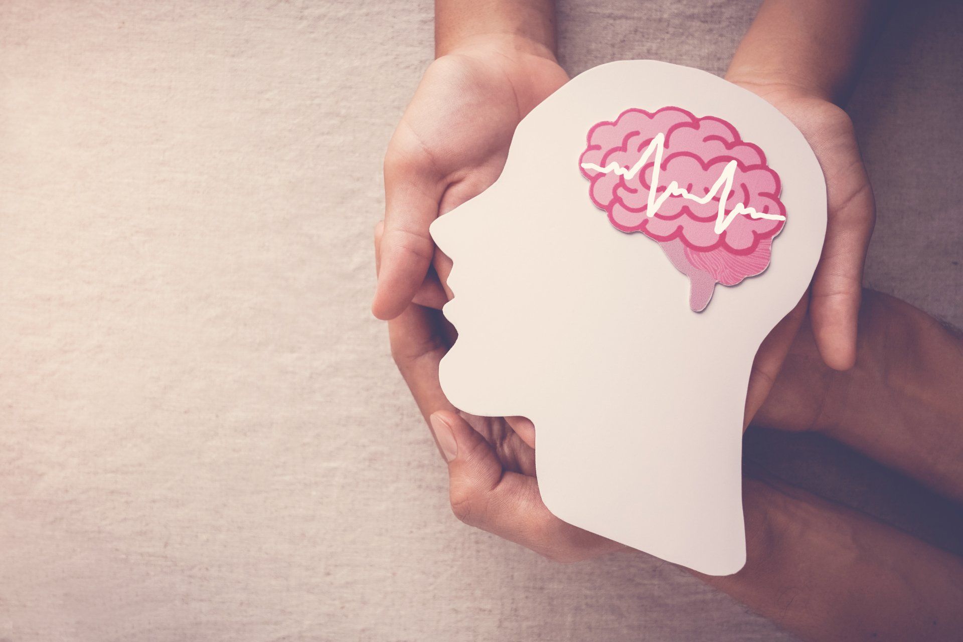 Una persona tiene in mano una testa di carta con un cervello e un battito cardiaco