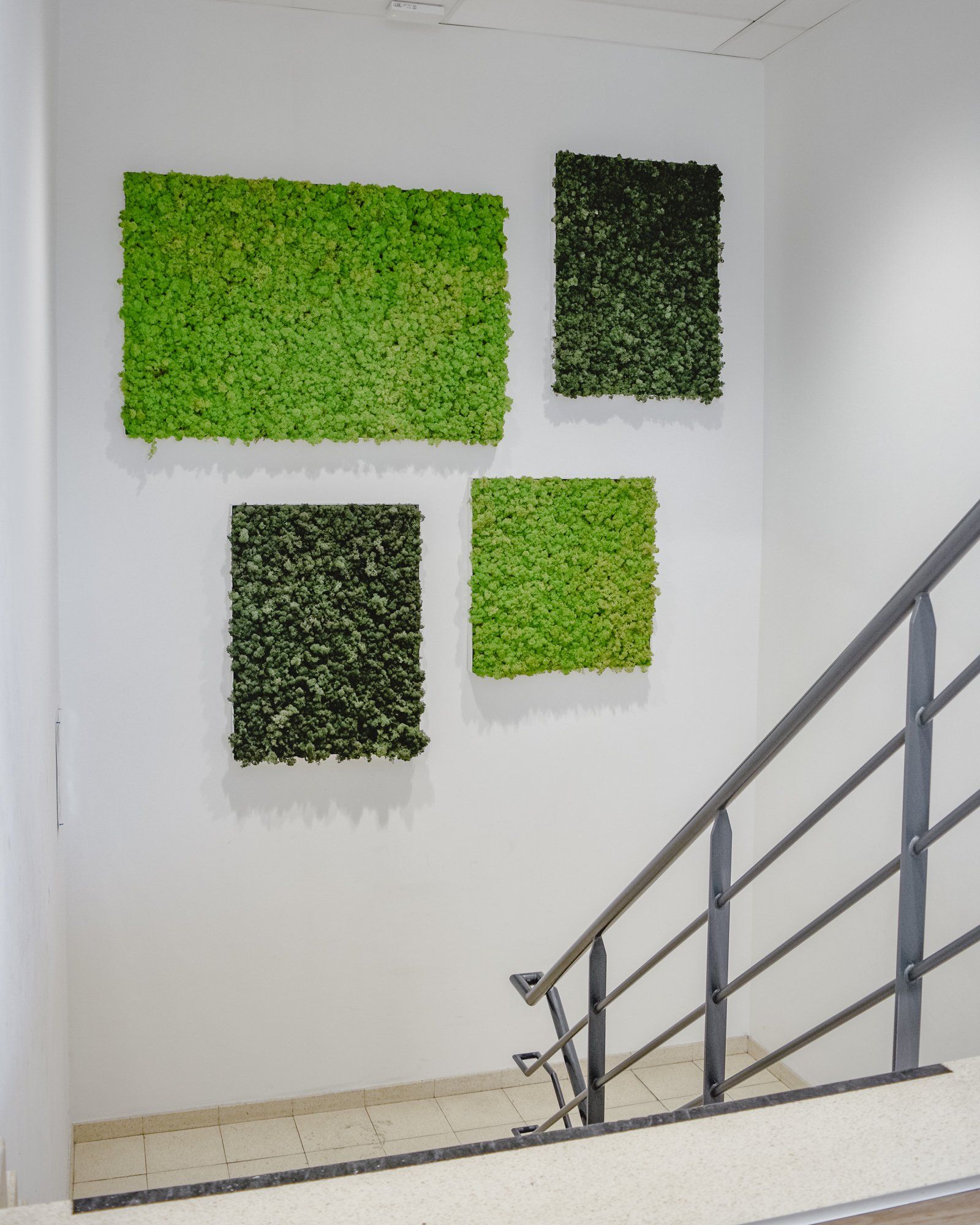 Mur de cage d'escalier avec quatre panneaux végétaux carrés verts au-dessus d'une rambarde