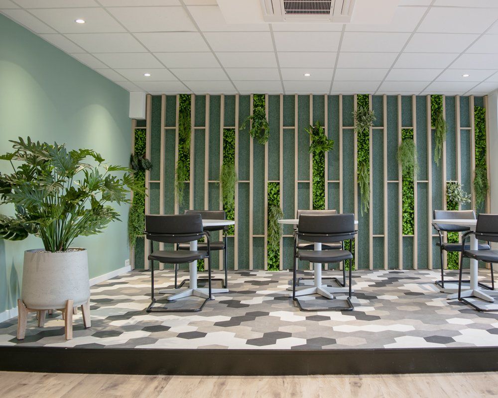 Salon moderne avec chaises noires, plante en pot et mur à lattes verticales vertes sur un tapis à motifs.