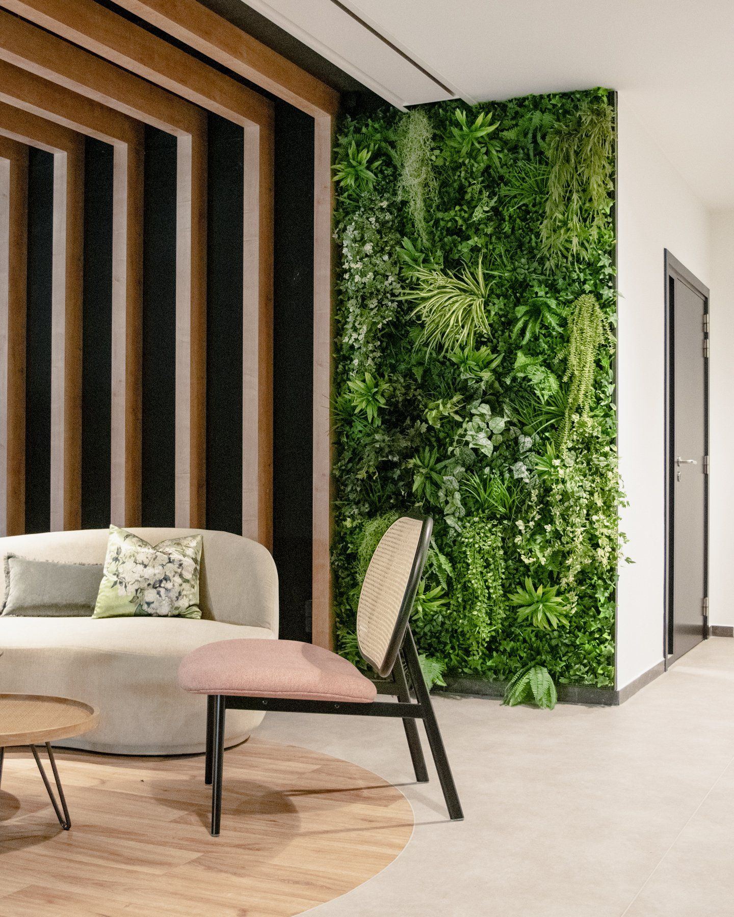 Salon moderne avec un canapé crème, un mur d'accent en bois et un mur végétal luxuriant.