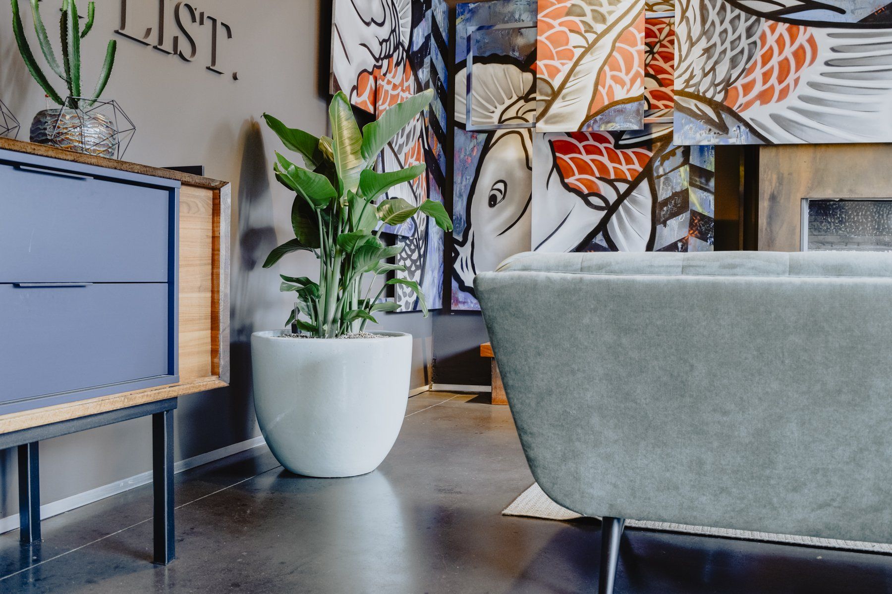 Modern office lounge with gray sofa, white potted plant, and colorful wall art