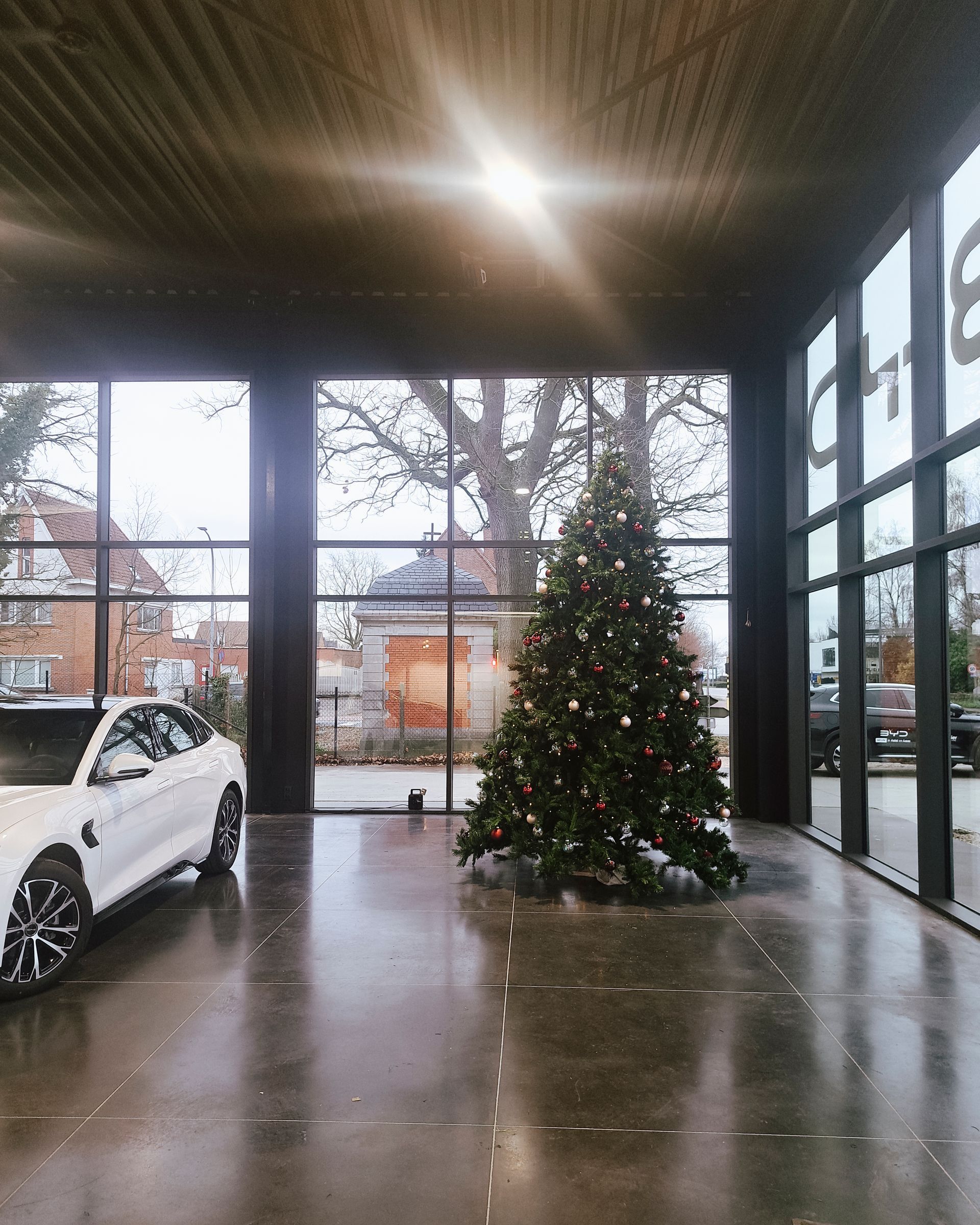 Modern showroom with a white car and a decorated Christmas tree on a glossy floor