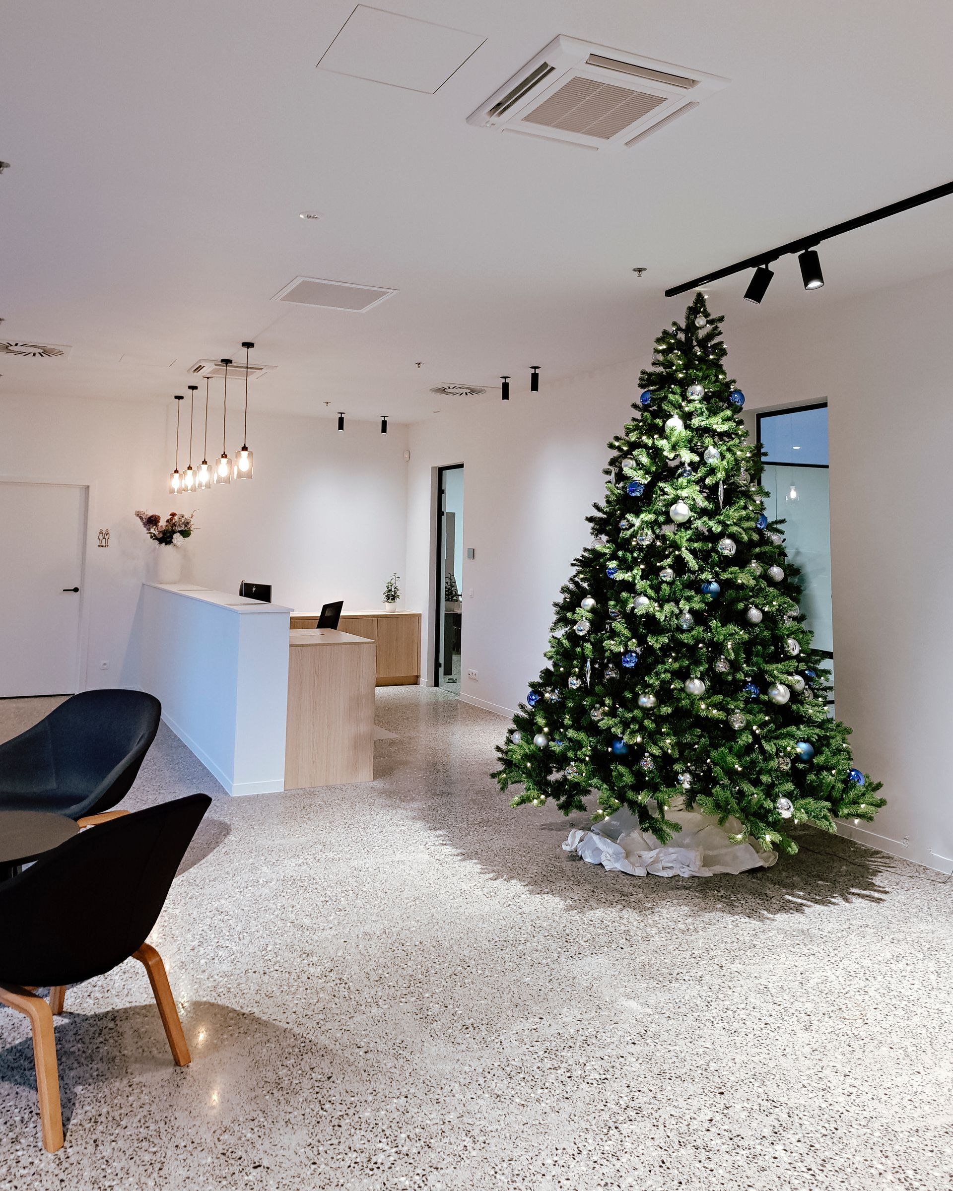 Modern office lobby with a decorated Christmas tree and minimalist seating on a speckled floor
