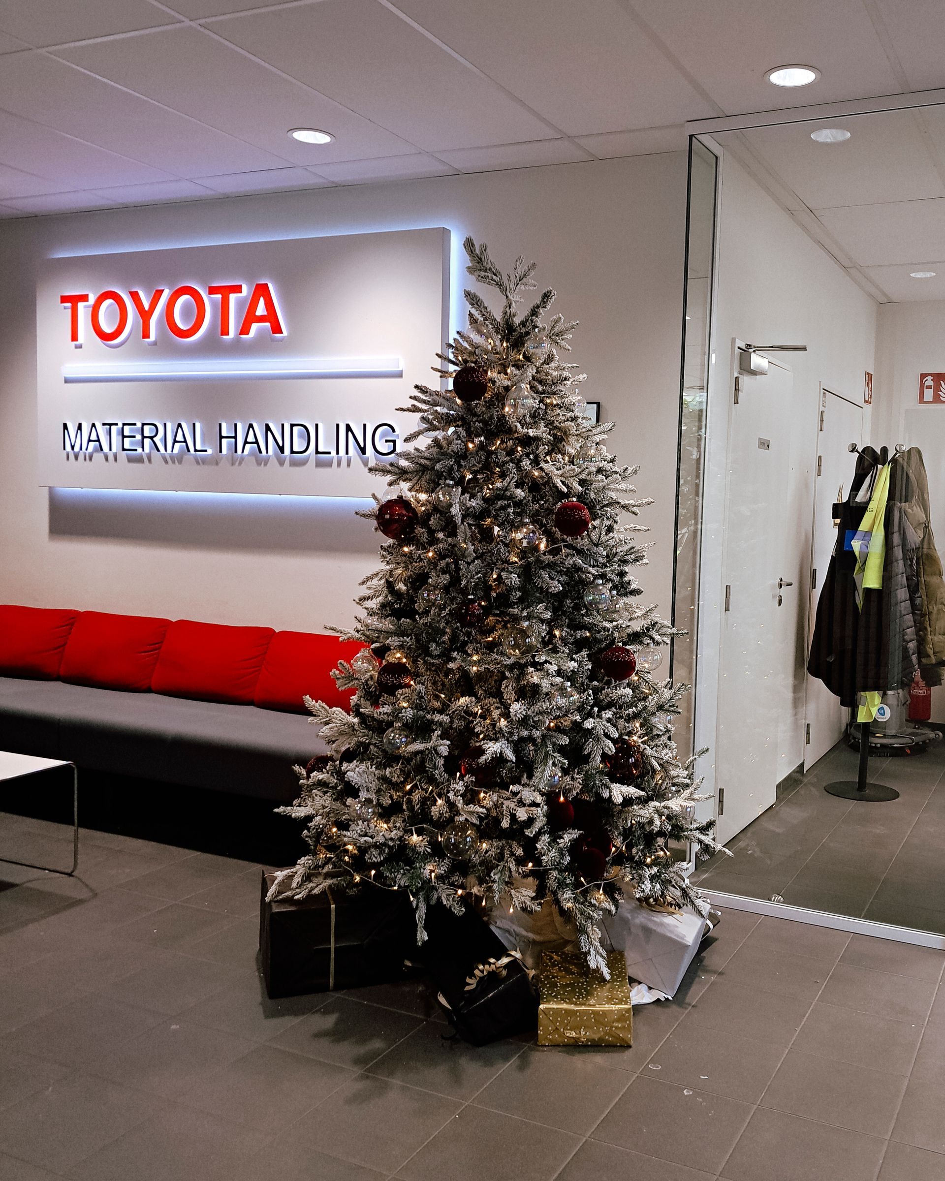 Toyota dealership lobby with a decorated Christmas tree beside a red bench and coats hanging nearby