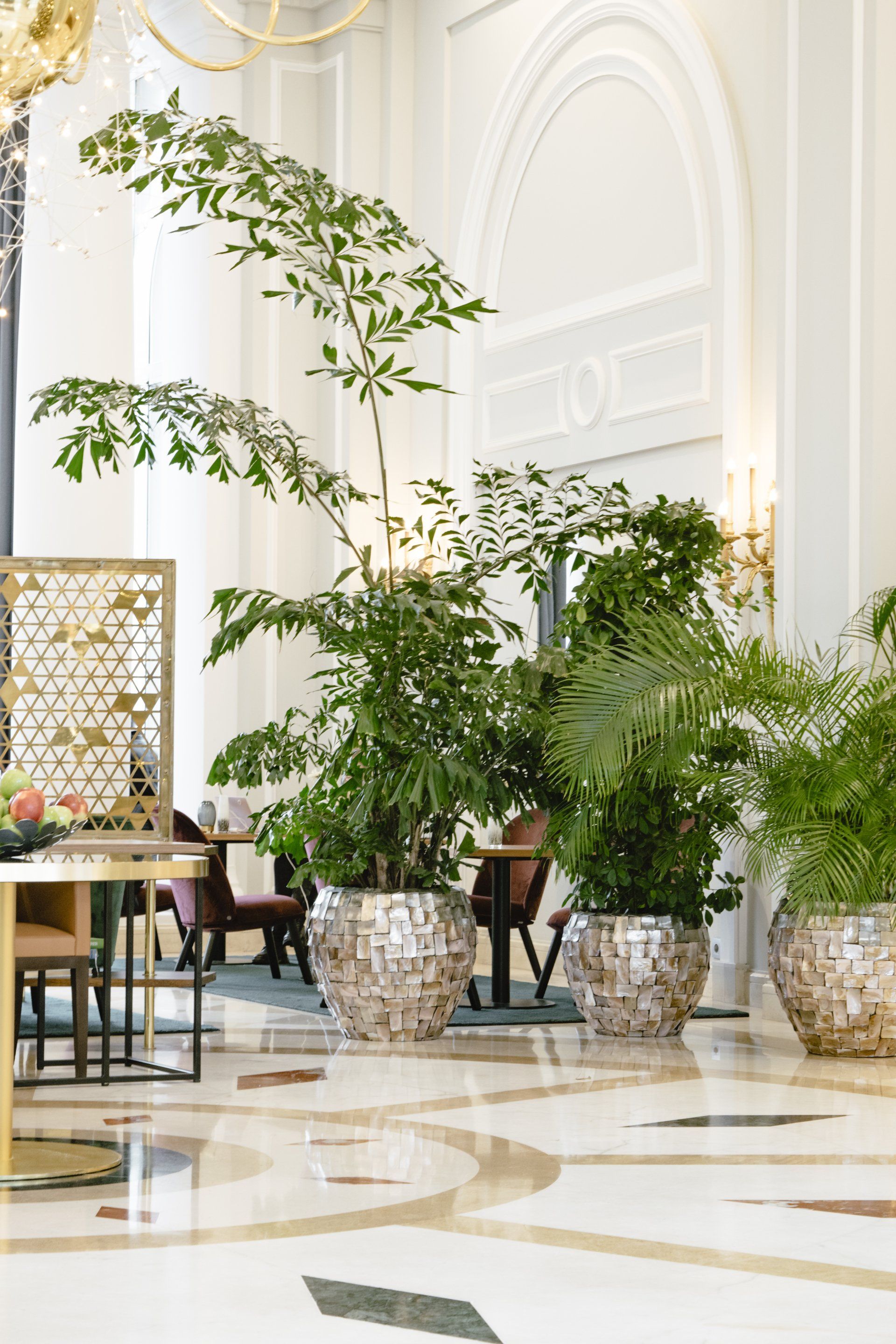Élégant atrium intérieur avec palmiers en pot, chaises ornées et sol en marbre poli