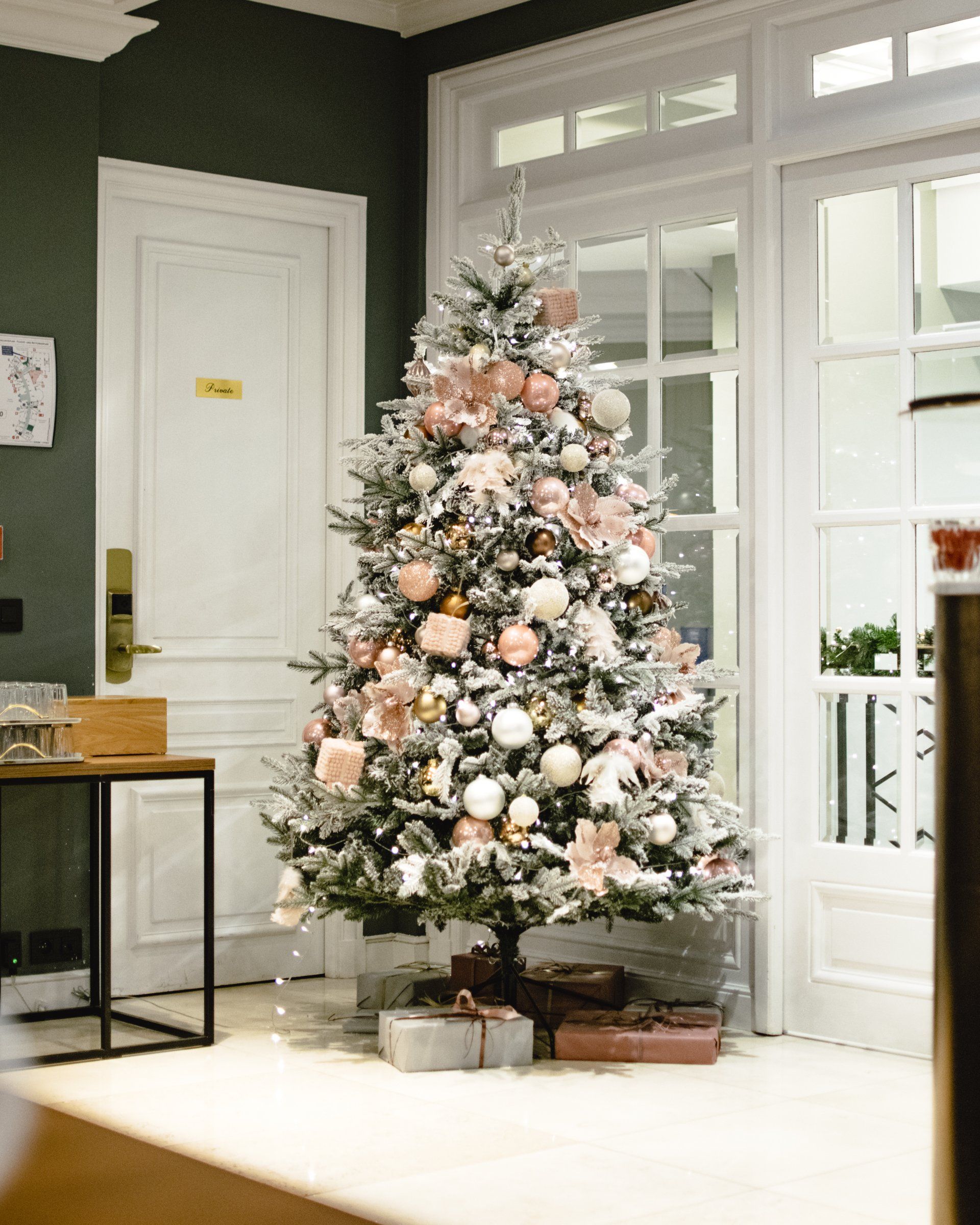 Decorated Christmas tree with white and pink ornaments in a bright room by glass doors