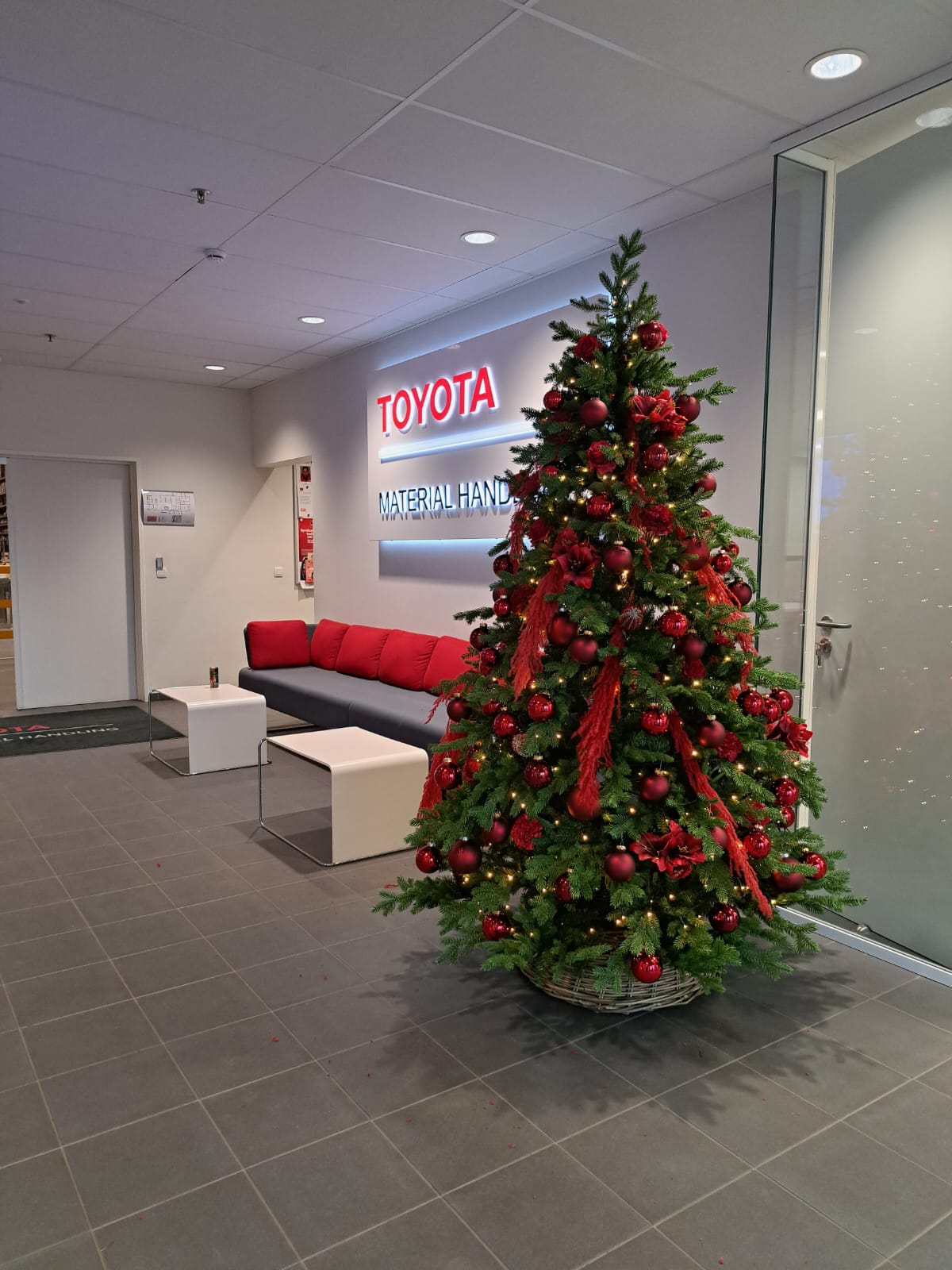 Lobby with a lit Christmas tree, red couch, and Toyota sign on the wall.