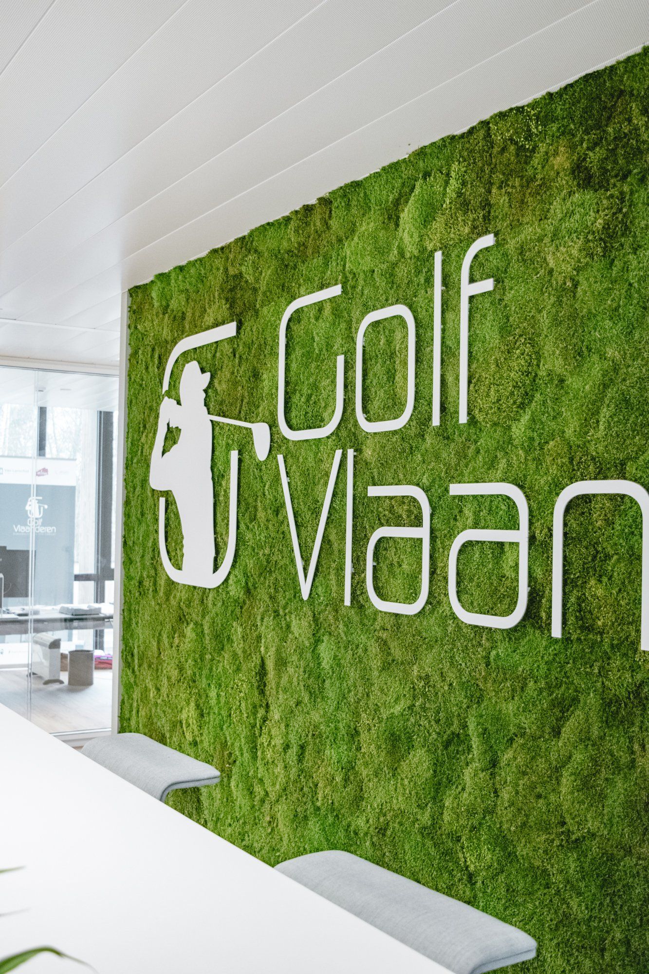 Mur recouvert de mousse verte avec une enseigne blanche « Golf Vlaan » dans le hall d'un immeuble de bureaux moderne