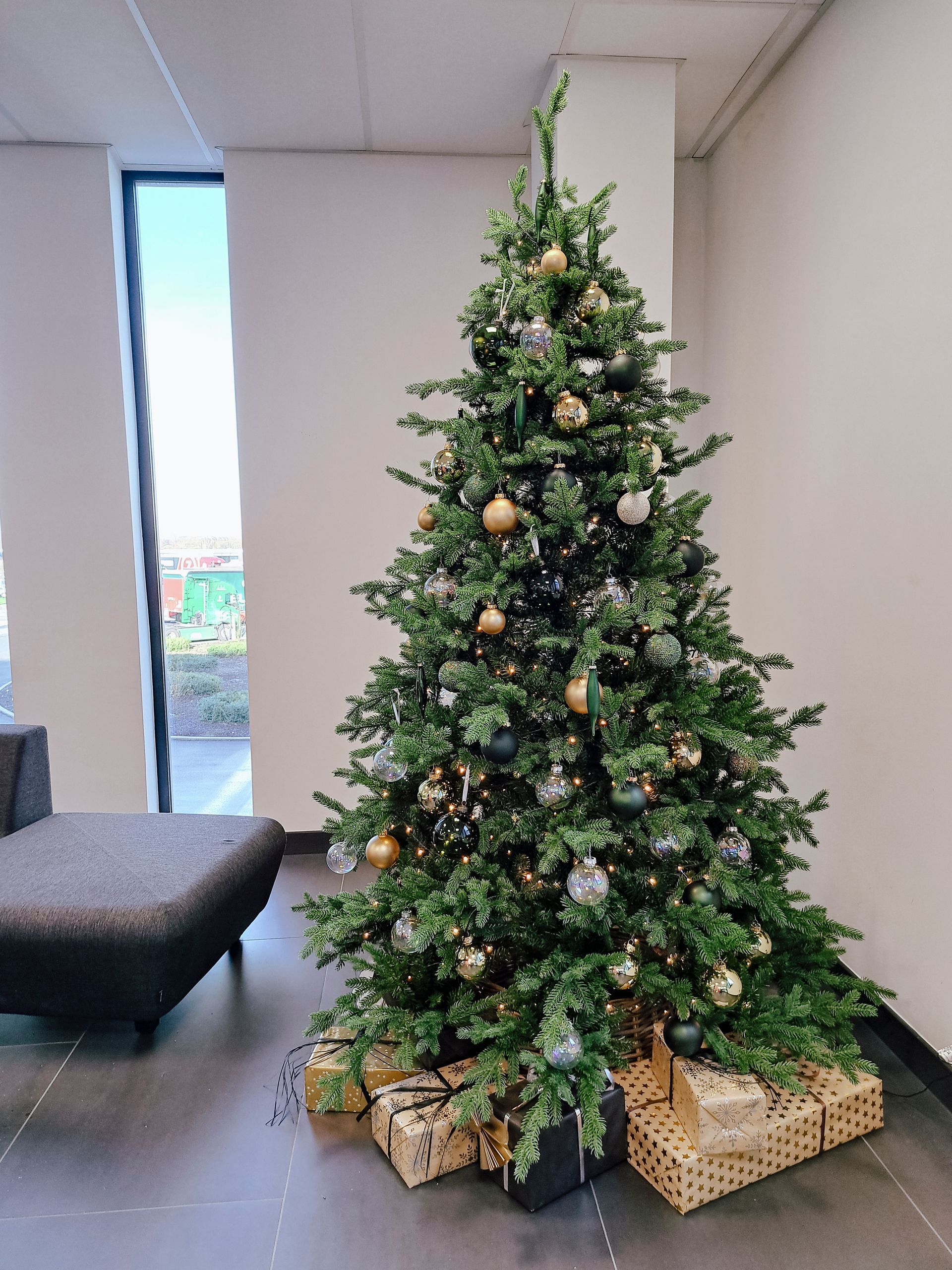 Decorated Christmas tree with gold ornaments and wrapped gifts in a modern room