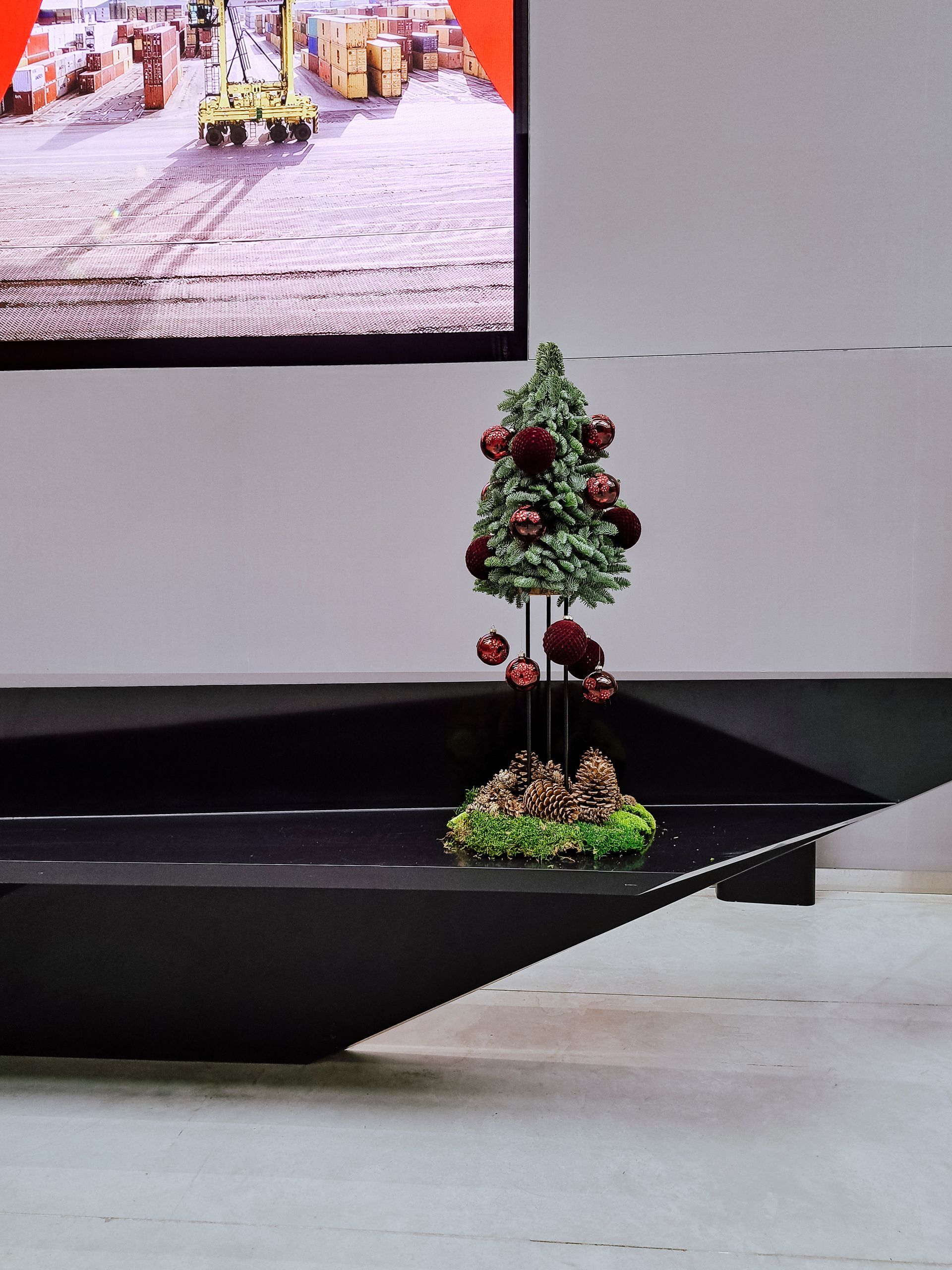 Miniature decorated Christmas tree on a black display platform in an indoor setting