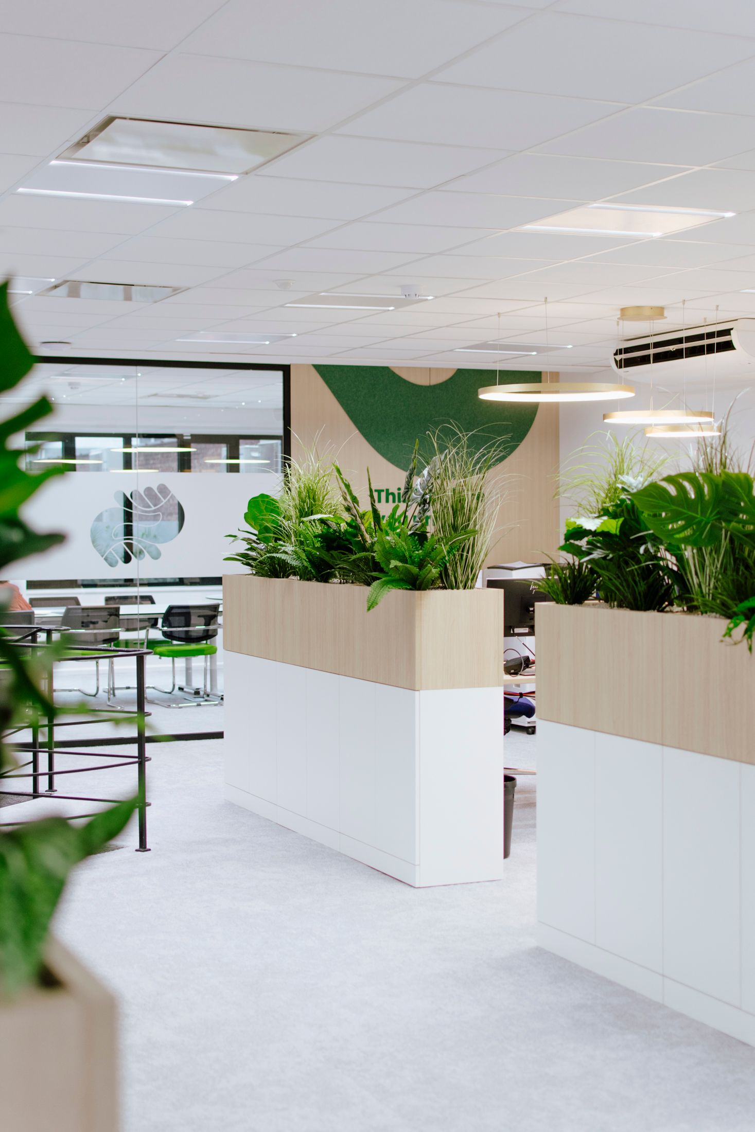 Hall d'entrée moderne avec sol blanc, plantes en jardinières et cloisons vitrées.