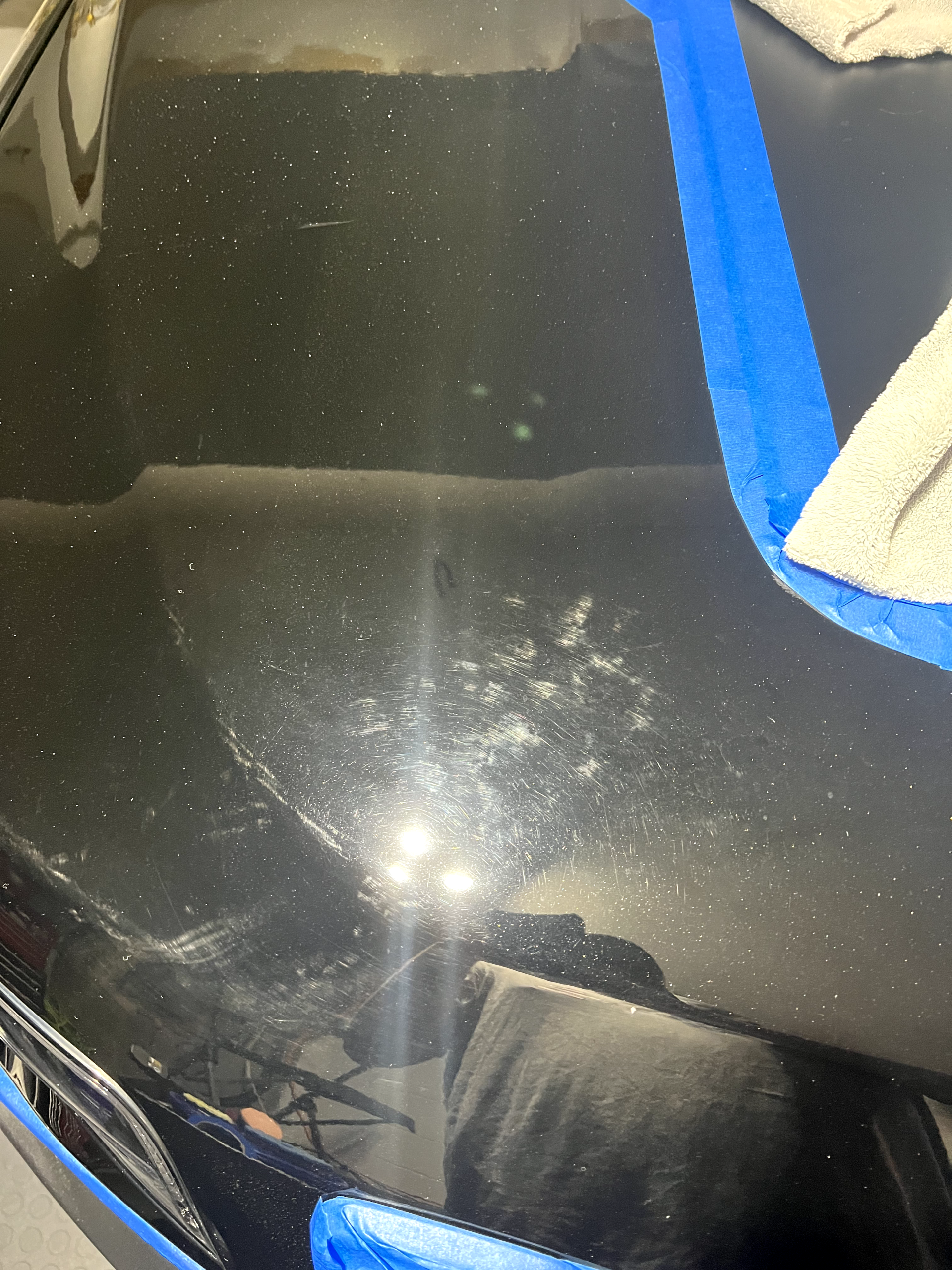 a close up of a black car hood with blue tape on it