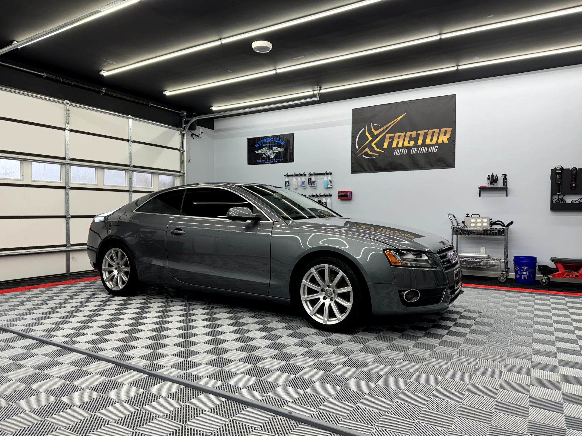 a gray car is parked in a garage next to a garage door .