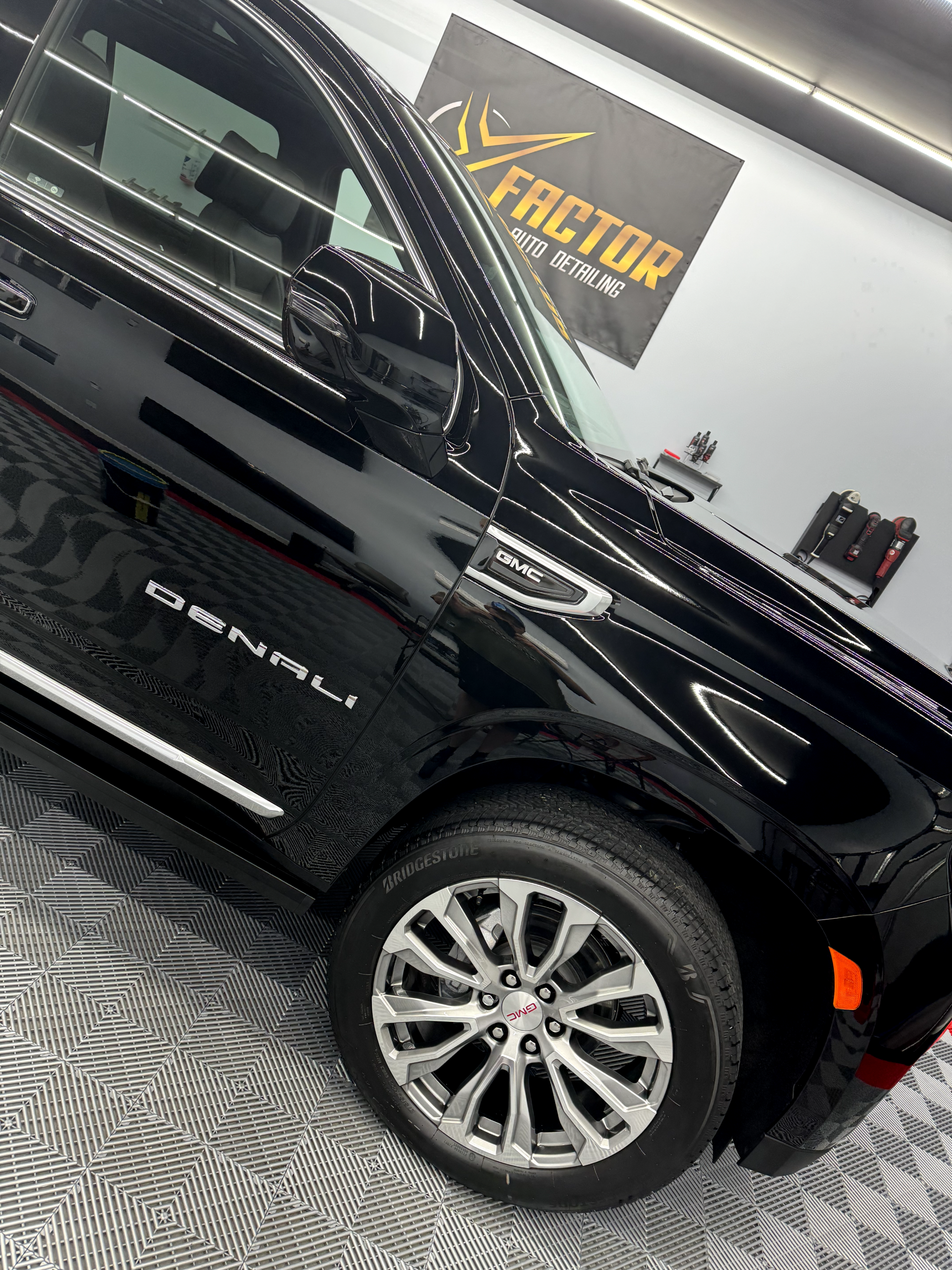 a black car is parked in a garage next to a sign that says factor .